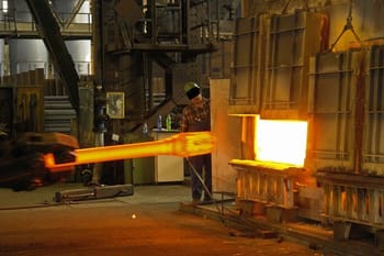 Metal smith inserting steel into hot furnace. Custom Steel Forging Process